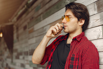 Stylish man in a city. Elegant male use the electronic cigarette