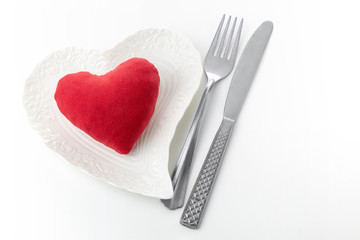 Red soft woolen heart on a white plate heart shape. Minimal Valentine's day celebration concept.