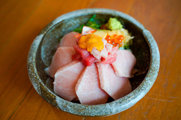 Close up premium  Donburi slice raw Otoro Maguro Japanese rice bowl. This menu on top of salmon eggs and wasabi,serve in Japanese traditional cwramic bowl  put on wooden table in Japanese restaurant.