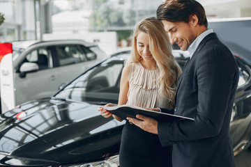 Couple in a car salon. Family buying the car. Elegant woman with her boyfriend