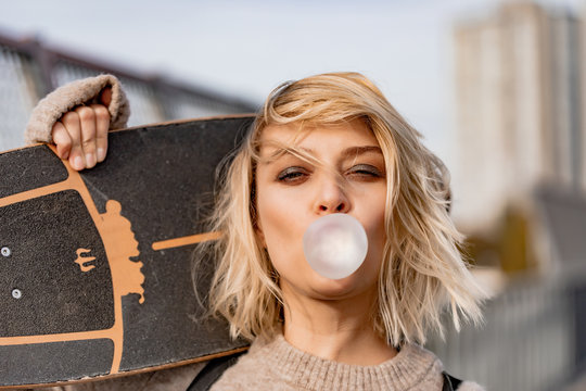 Urban stylish young girl. Outdoors emotional portrait of active woman model. Healthy lifestyle. Fashion look, outdoor hipster portrait. Close up portrait of a pretty young girl chewing bubble gum.