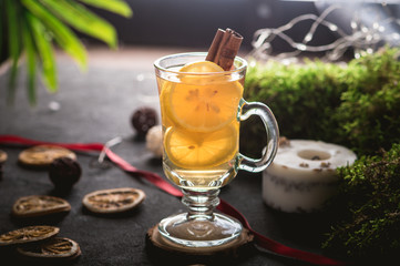Hot tea with lemon and cinnamon on dark background
