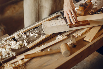 Man working with a wood. Carpenter in a white shirt
