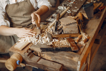 Man working with a wood. Carpenter in a white shirt