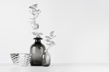 Elegant black and white home decor - black glass vase decorated silver leaves, bowl on light white wood table.