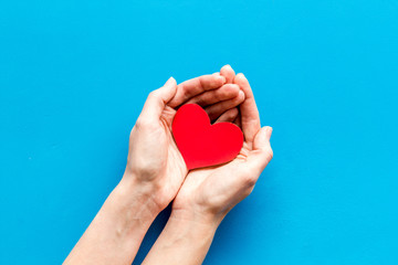 Heart icon. Paper heart in hands on blue background top view copy space