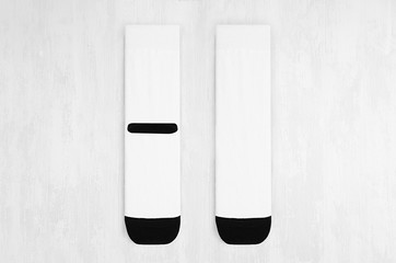 Pair blank white tall socks with black heel flat lay on white wood board, front view, backside -...