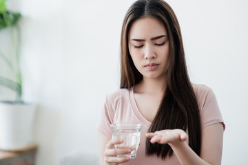 Close up shot of sick woman's hand holding pills and water. Medical, healthy concept.