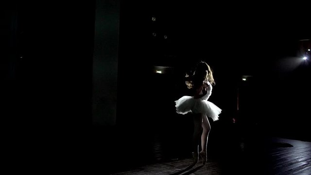 Graceful ballerina dancing on stage with magic light. Beautiful young ballerina performing professional classic dance in theatre in spotlight. classical ballet dancer performance white tutu lanterns