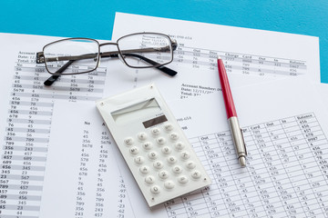 Taxes calculation concept. Financial documents, calculator, glasses on blue background