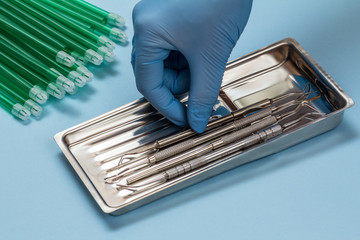 Dentist's hand with set of metal dental instruments for teeth dental care