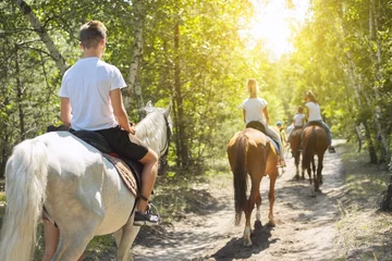 Fotobehang Group of teenagers on horseback riding in summer park © Valerii Honcharuk
