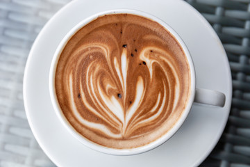 Hot latte art coffee heart shape in a white cup on table