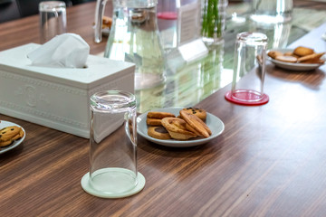 Business people sitting on a table for conference with cookies glass and jar of water placed on wooden table