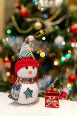 snowman with a gift under the Christmas tree