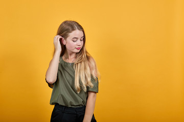 Attractive young pretty woman wearing nice pastel shirt and with nice haircut,looking calm and takes hand on head, over isolated orange background