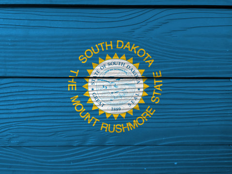 South Dakota flag color painted on Fiber cement sheet wall background. The sun on sky blue with surrounded of gold text.