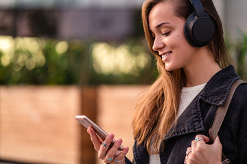 Stylish fashionable happy joyful hipster student woman teenager   listens to music using wireless...