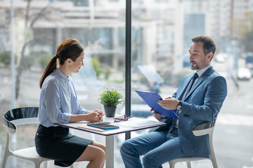 Secretary smiling while speaking with businessman and discussing tasks for the day