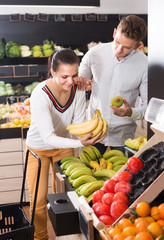 Buyers choosing various fruits in grocery store