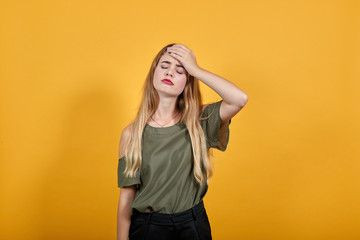 Relaxed young woman in casual clothes keeping eyes closed, with hand behind head isolated on orange wall background in studio. People sincere emotions, lifestyle concept.