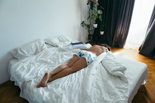 woman laying on the bed white sheets light from window with curtains