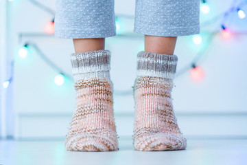 Female legs in warm knitted soft cozy socks in wintertime at home.