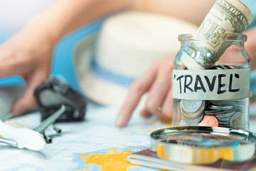 Fototapeta na wymiar Saving money in a glass jar for travel on map