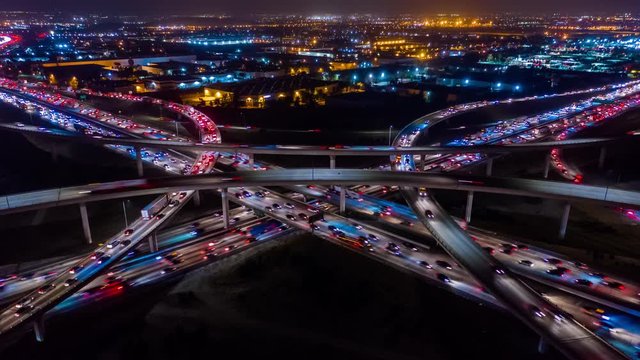 Urban aerial time-lapse in motion drone shot of freeways and interstate with heavy traffic at night.