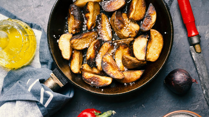 Fried potatoes in a pan on a gray concrete table.
