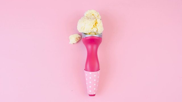 Ice cream cones and scoop overhead flat lay on pink wood table, real time.