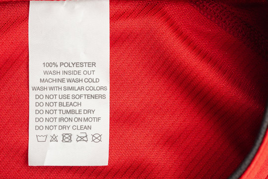 White laundry care washing instructions clothes label on red jersey polyester sport shirt