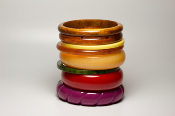 Close up view of vintage bakelite bangle bracelets in varying colors and widths on white background