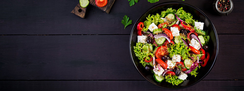 Healthy food. Greek salad with cucumber, tomato, sweet pepper, lettuce, red onion, feta cheese and olives.  Top view, banner