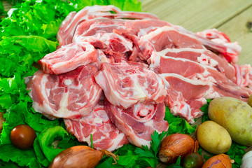 Pieces of fresh lamb meat on a wooden desk with  vegetables