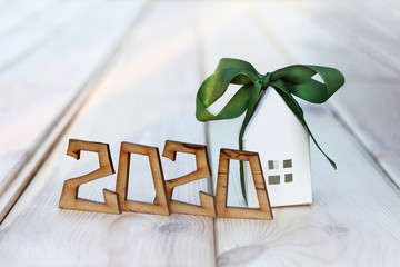 wooden numbers form the number 2020 and a paper house with a green ribbon. individual real estate is a good gift
