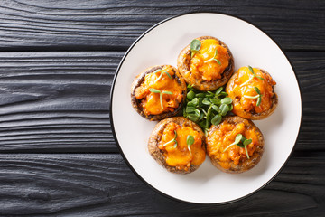 Baked hot mushrooms stuffed with minced meat and cheddar cheese close-up on a plate. Horizontal top view