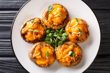 Mushrooms champignons stuffed with minced meat and cheddar cheese close-up on a plate. Horizontal top view