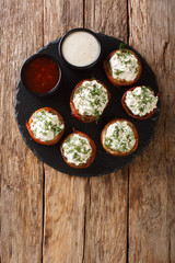 Mushrooms stuffed with cream cheese wrapped in bacon close-up on a plate. Vertical top view