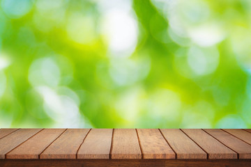 Empty plank brown wood table top with blur green tree texture background.