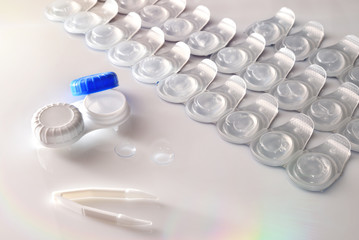 Contact lenses blister and case on white table elevated