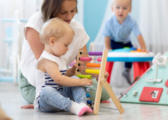 Kids playing on floor with developmental toys in kindergarten. Children have fun in nursery or...