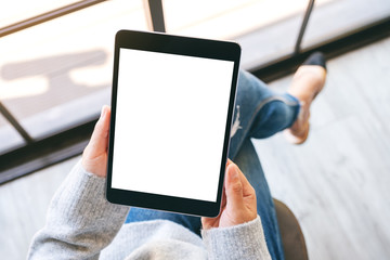 Top view mockup image of a woman holding black tablet pc with blank white screen