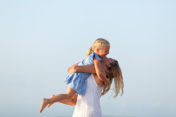 Portrait of happy sisters. They hug on the background of the sea.