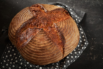 Freshly baked Artisan sourdough bread loaves with kitchen towel on black concrete backgroun