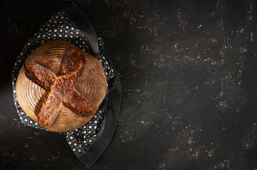 Freshly baked Artisan sourdough bread loaves with kitchen towel on black concrete backgroun