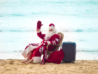 Santa claus resting on the seashore raising his hand up