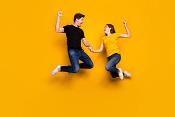 Fototapeta na wymiar Full body photo of crazy guy lady couple jump high raise fists celebrate first place football league favorite team wear casual jeans t-shirts isolated yellow color background