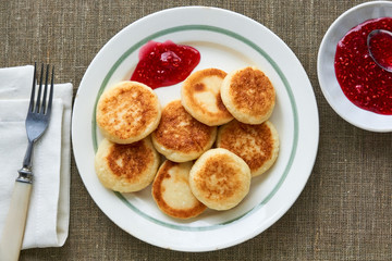 Cottage cheese pancakes with raspberry jam on a white plate 