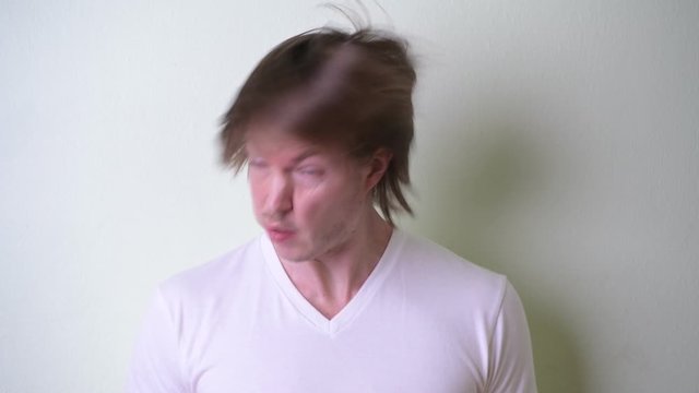 Face of young man with long hair banging head